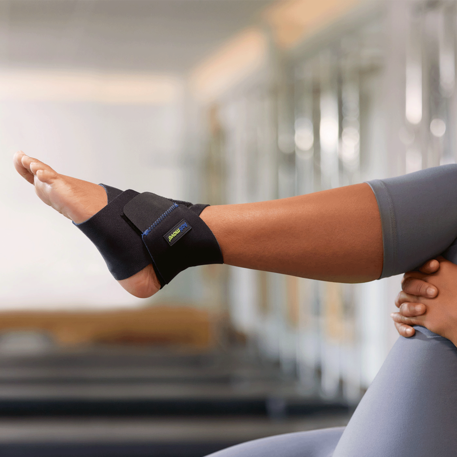 Lifestyle image of woman wearing Actimove Sport Ankle Support Adjustable while stretching/ doing yoga