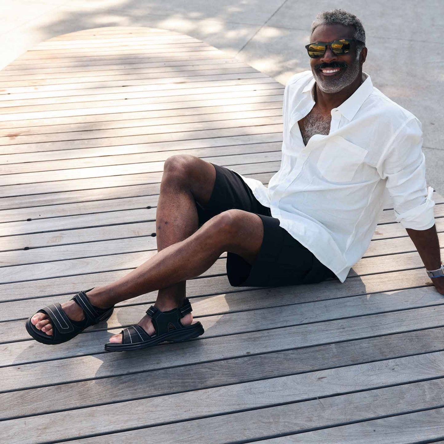 Man sitting on ground outside smiling and wearing the Men's Hudson shoes