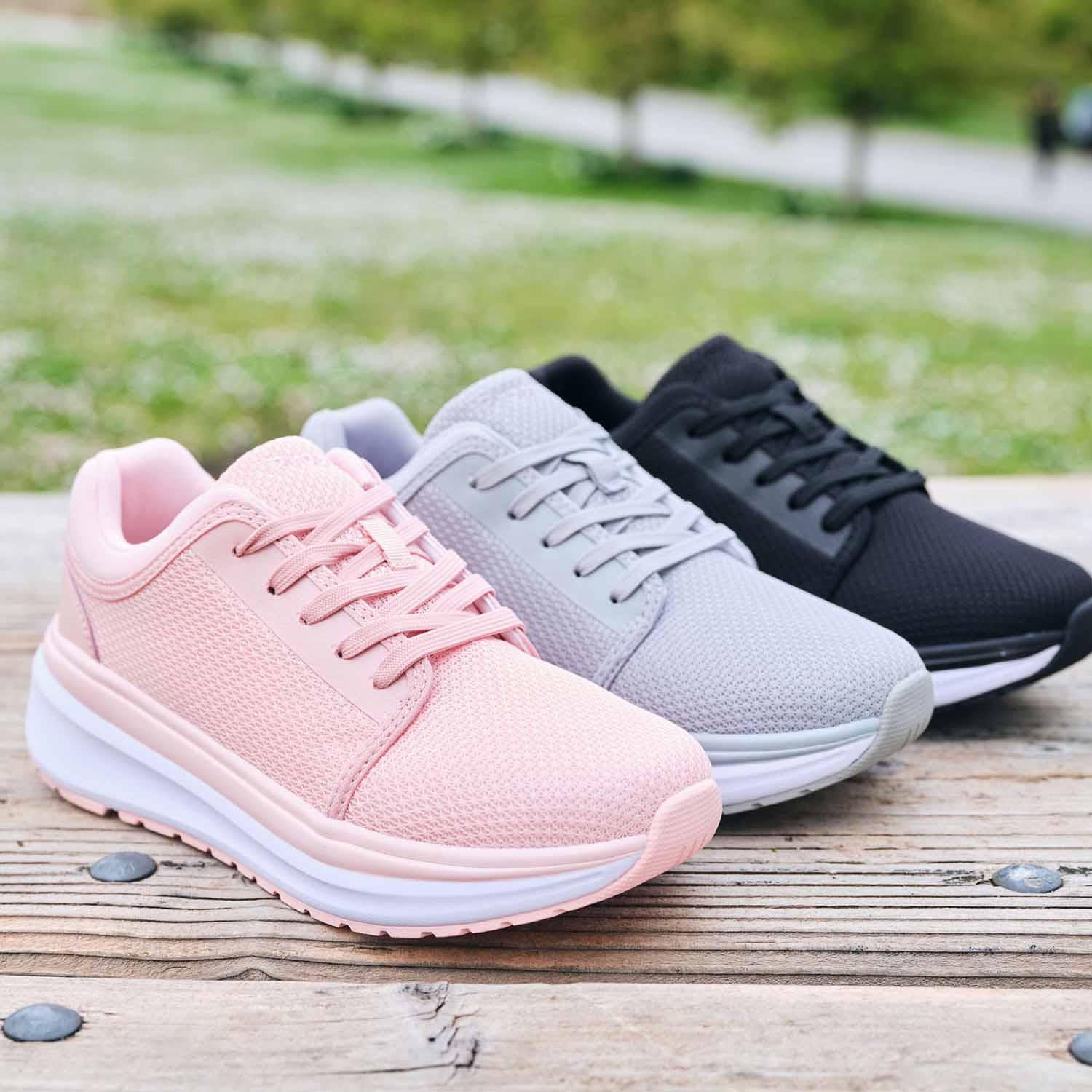 All 3 Ultima X Athletic Shoes in different color options available side-by-side (Black, Grey, & Pink) on wooden surface outside